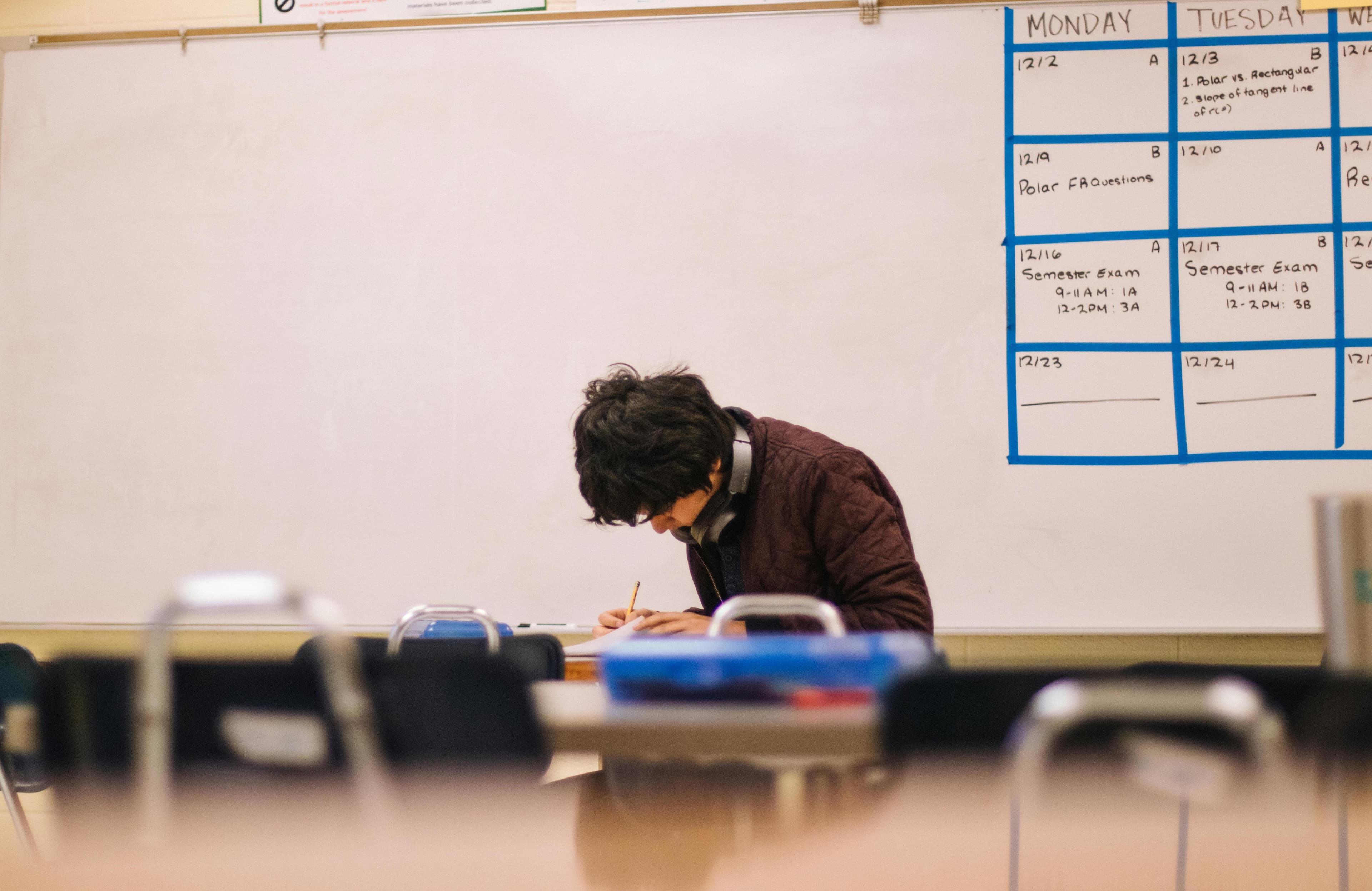 Student writing on paper in a classroom during study session
