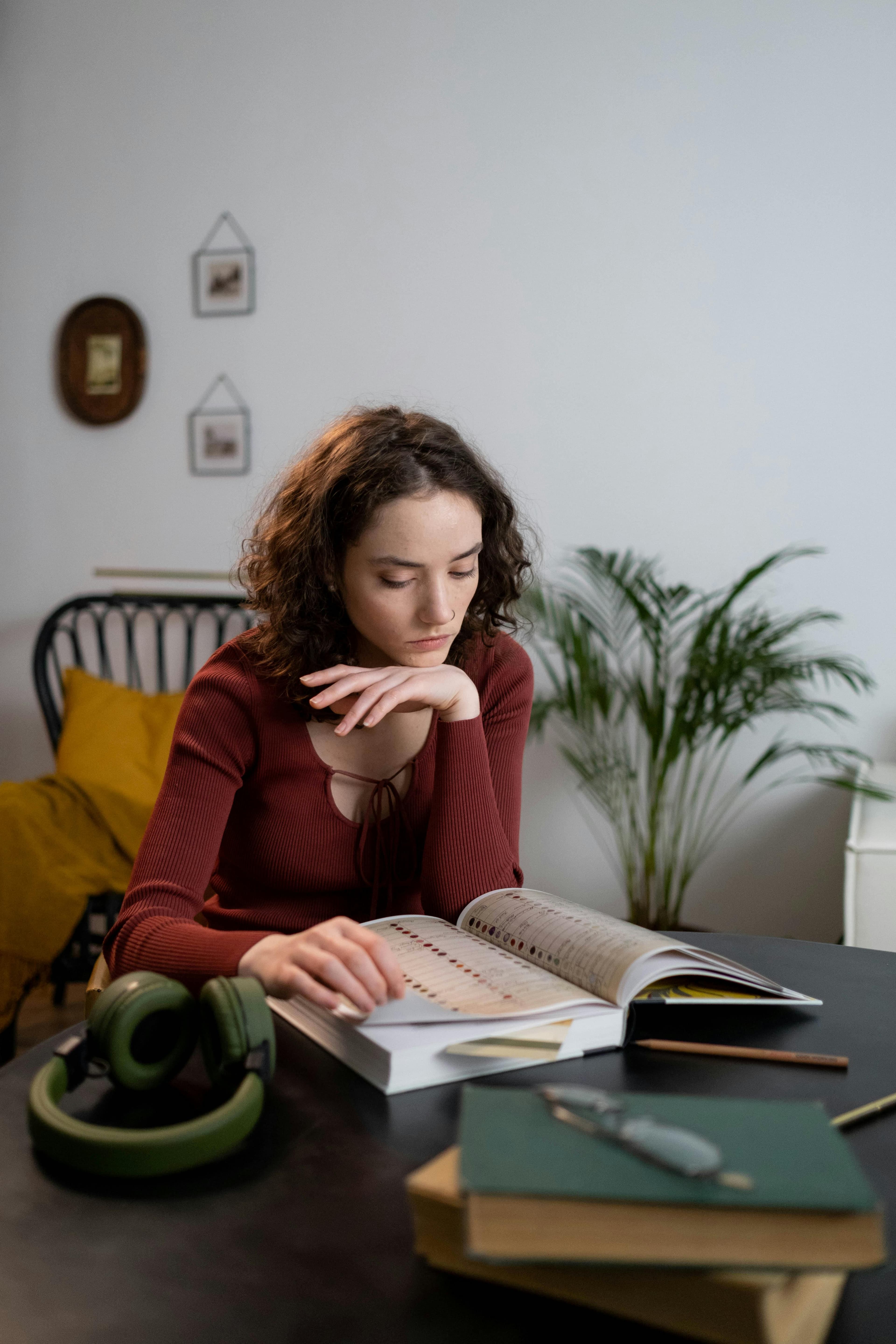 Focused student reading and taking notes from a textbook while studying at home.